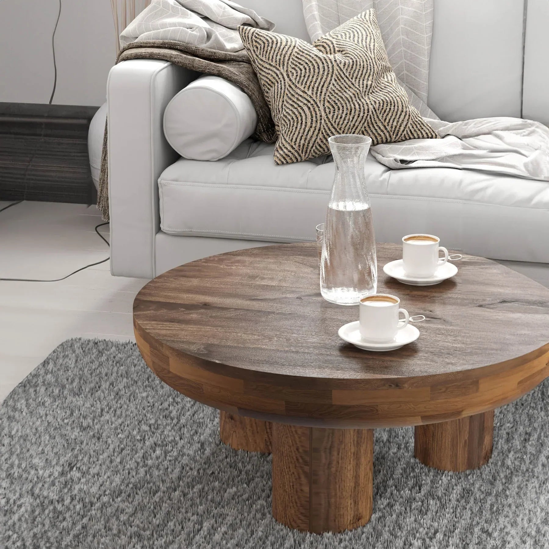 Front view of the Wilder round coffee table featuring a thick solid wood top and three chunky cylindrical pedestal legs
