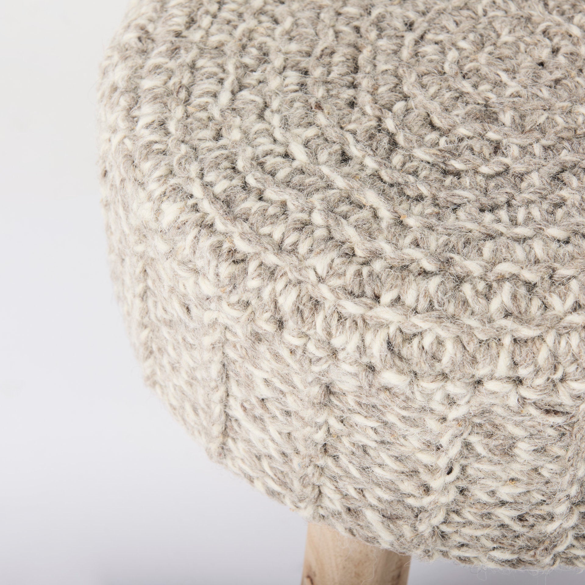 Front three-quarter view of the Bina accent stool featuring a thick gray knitted wool seat and four natural wood legs