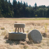 Lifestyle shot of the Bina stools in an outdoor field setting highlighting their organic and rustic aesthetic