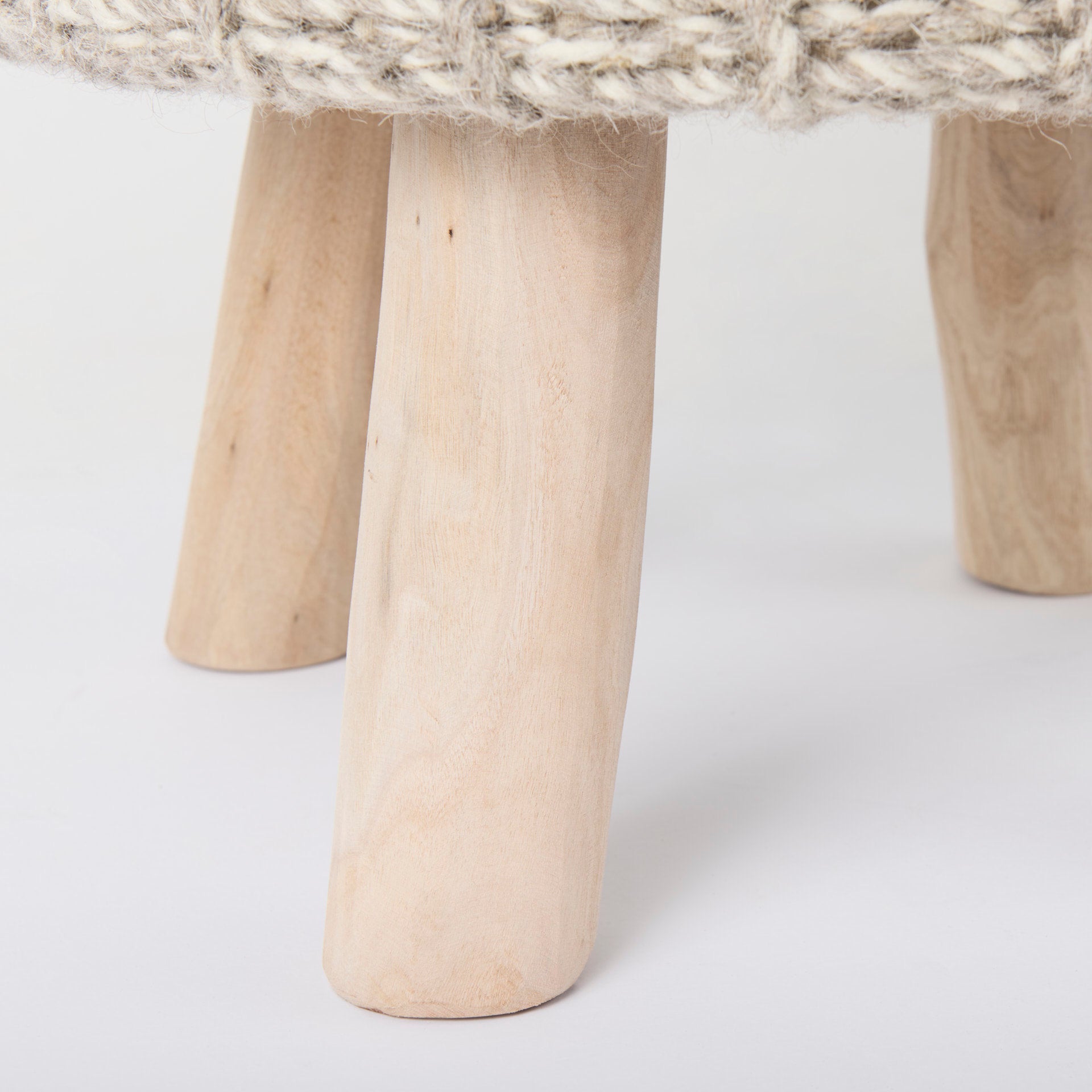 Front three-quarter view of the Bina accent stool featuring a thick gray knitted wool seat and four natural wood legs