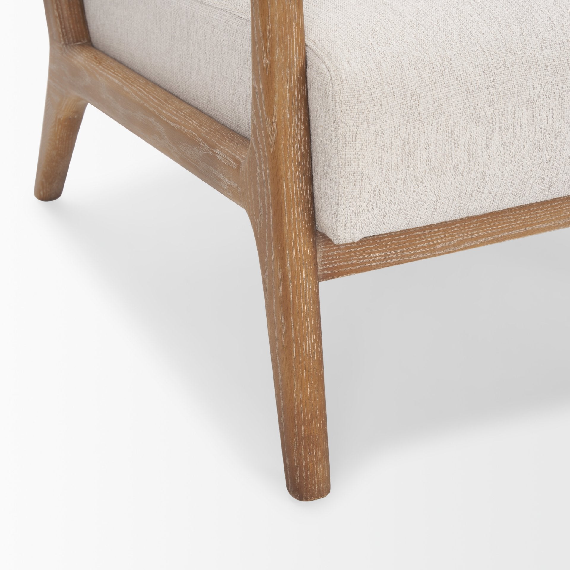 Macro shot of the light oak leg and the textured ivory fabric of the Cashel seat cushion