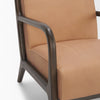 Macro shot of the dark-stained wood leg and the smooth tan leather upholstery