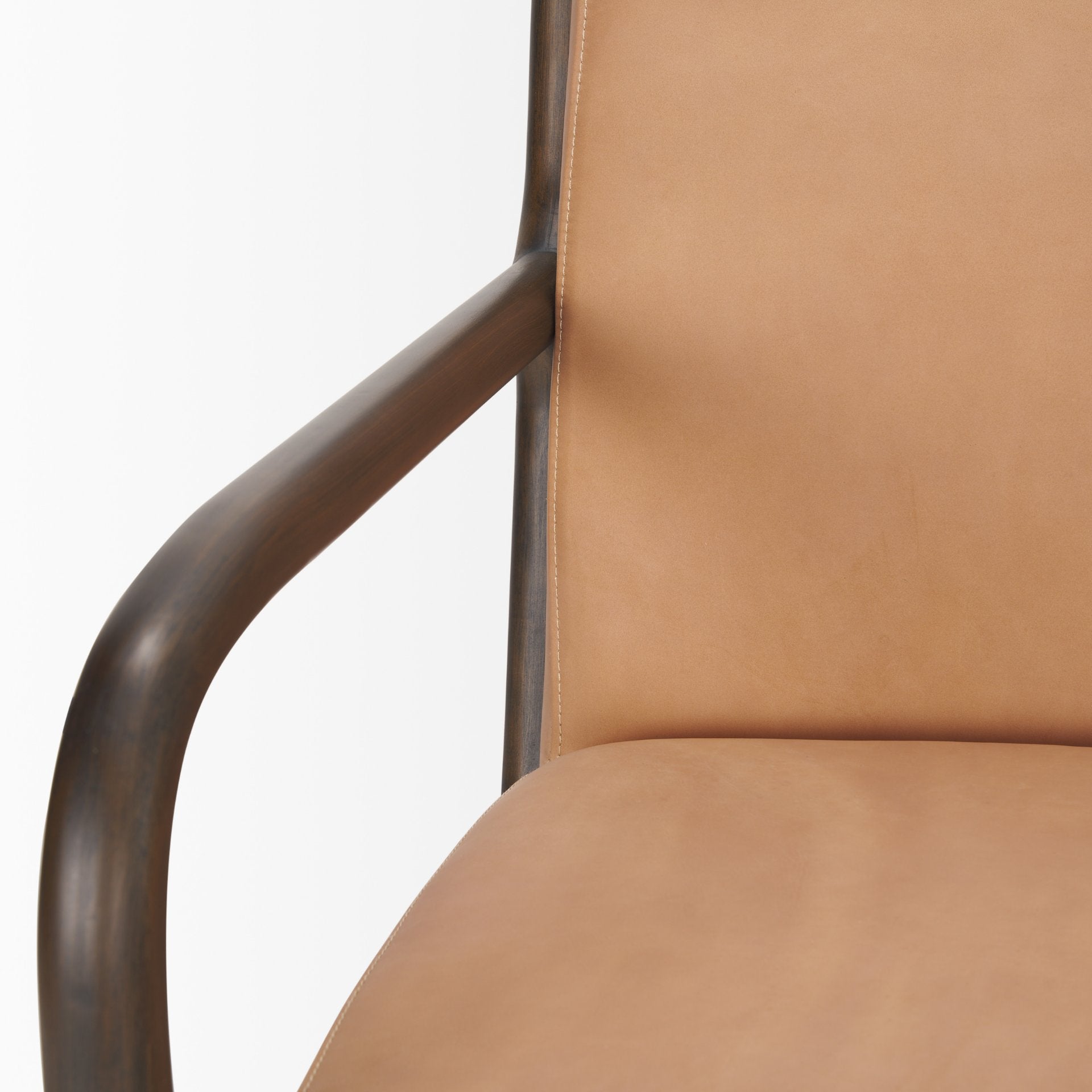 Detailed view of the dark wood armrest and tan leather seat on the Cashel chair