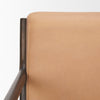 Close-up detail of the tan leather and dark wood frame at the top corner of the chair