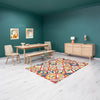 Perspective lifestyle shot showcasing the natural oak table and bench set over a vibrant geometric area rug