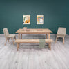 Wide-angle lifestyle view of the table in a clean minimalist space with large windows and simple decor