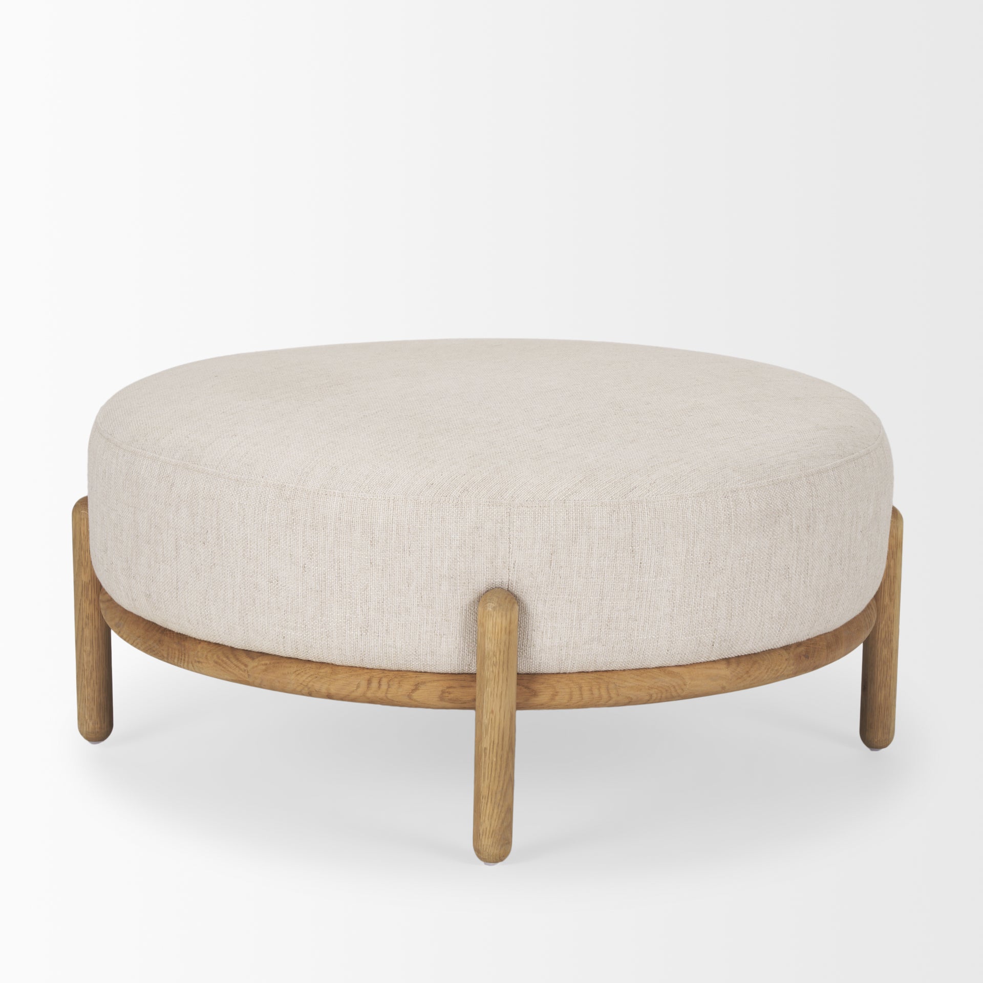 Front three-quarter view of the Gwynn ottoman featuring a cream upholstered seat and a curved oak wood frame