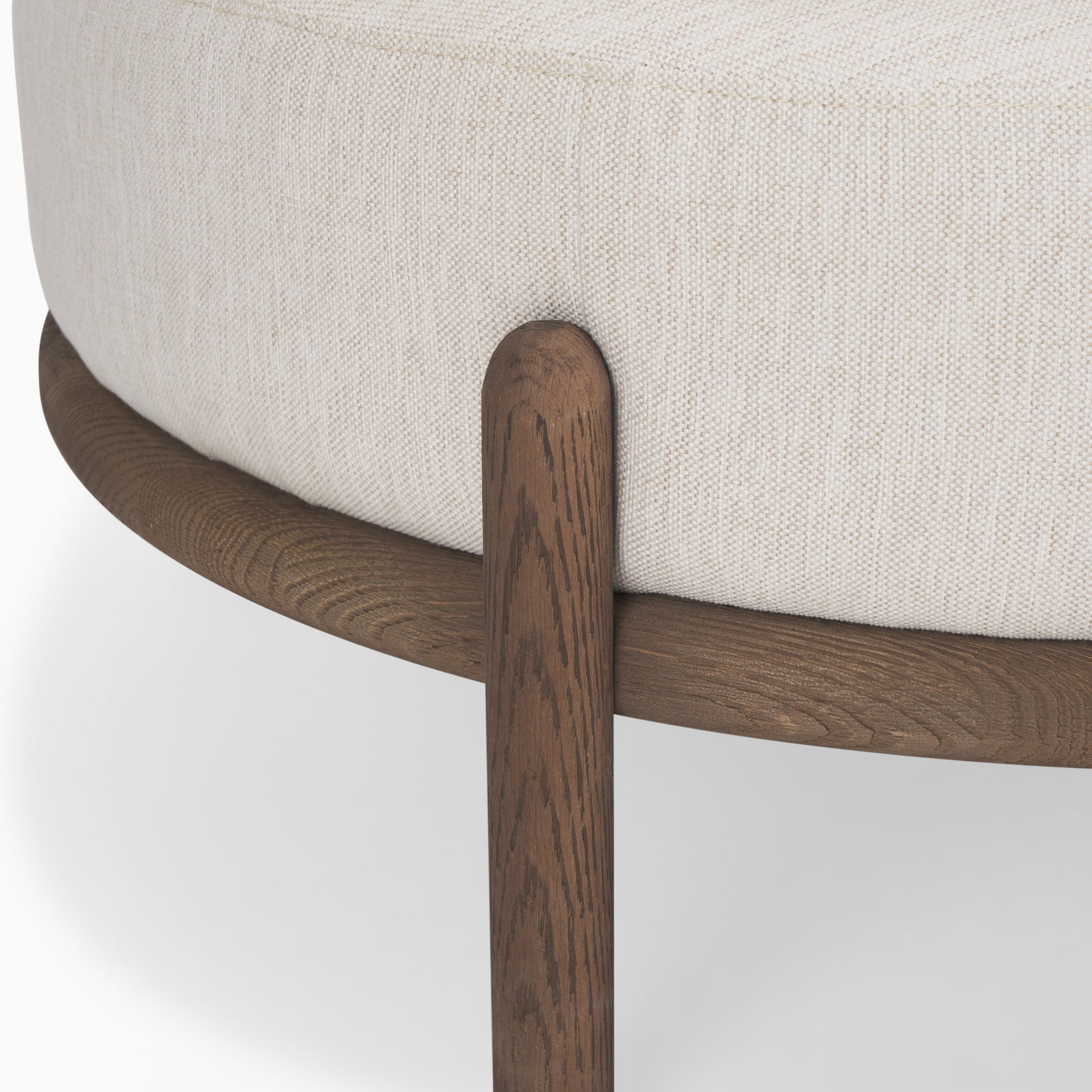 Front three-quarter view of the Gwynn ottoman featuring a cream upholstered seat and a curved oak wood frame