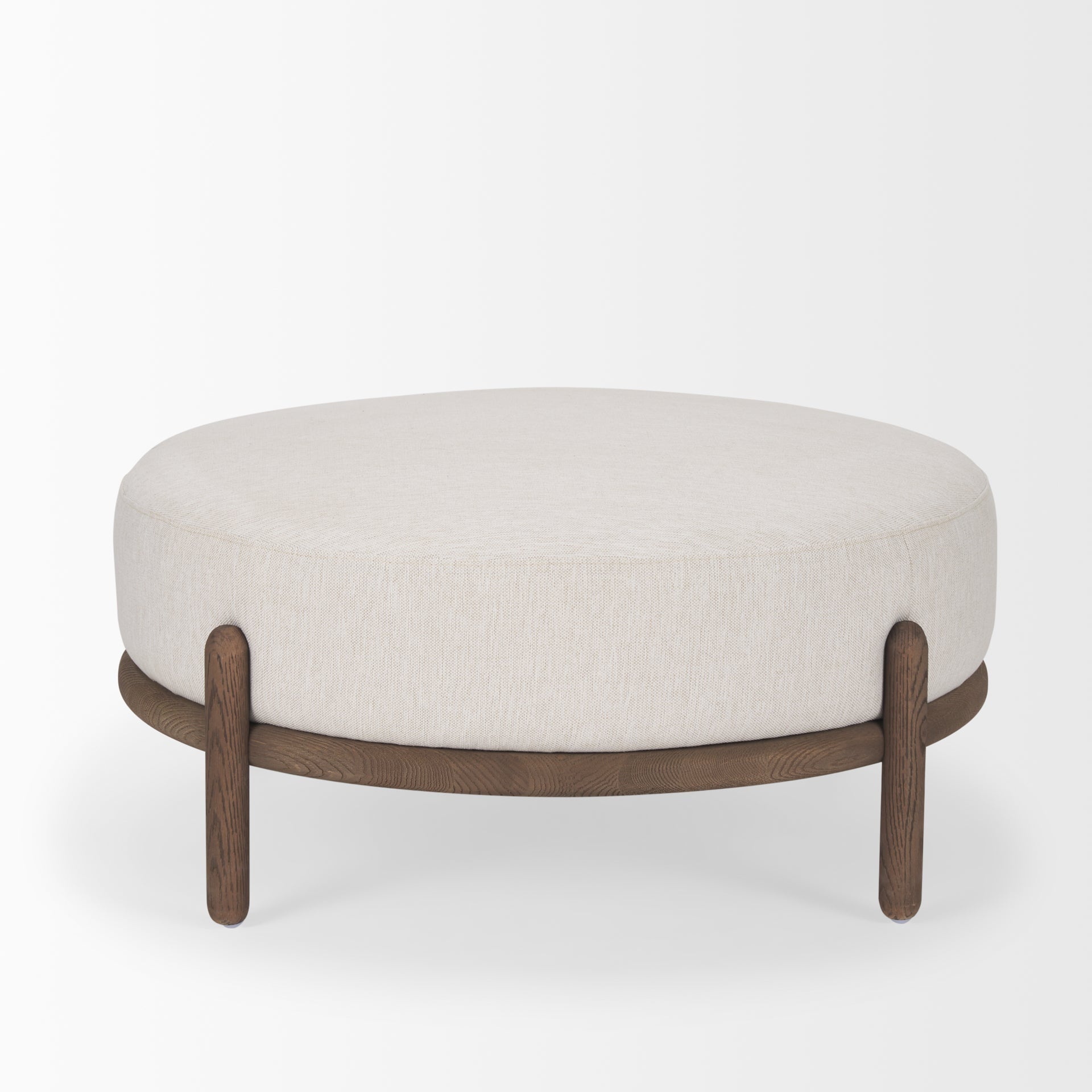 Front three-quarter view of the Gwynn ottoman featuring a cream upholstered seat and a curved oak wood frame