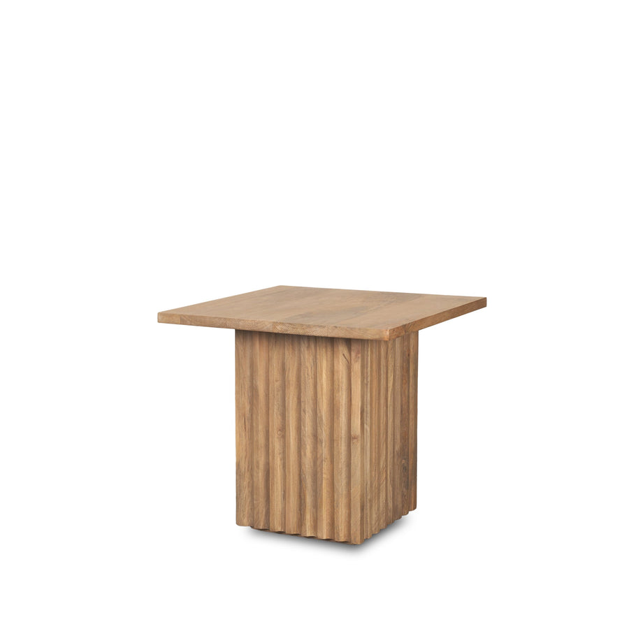 Perspective view of the June side table featuring a square tabletop and a thick square fluted pedestal base in natural mango wood
