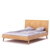 Three-quarter perspective view showcasing the low-profile frame and minimalist tapered solid wood legs