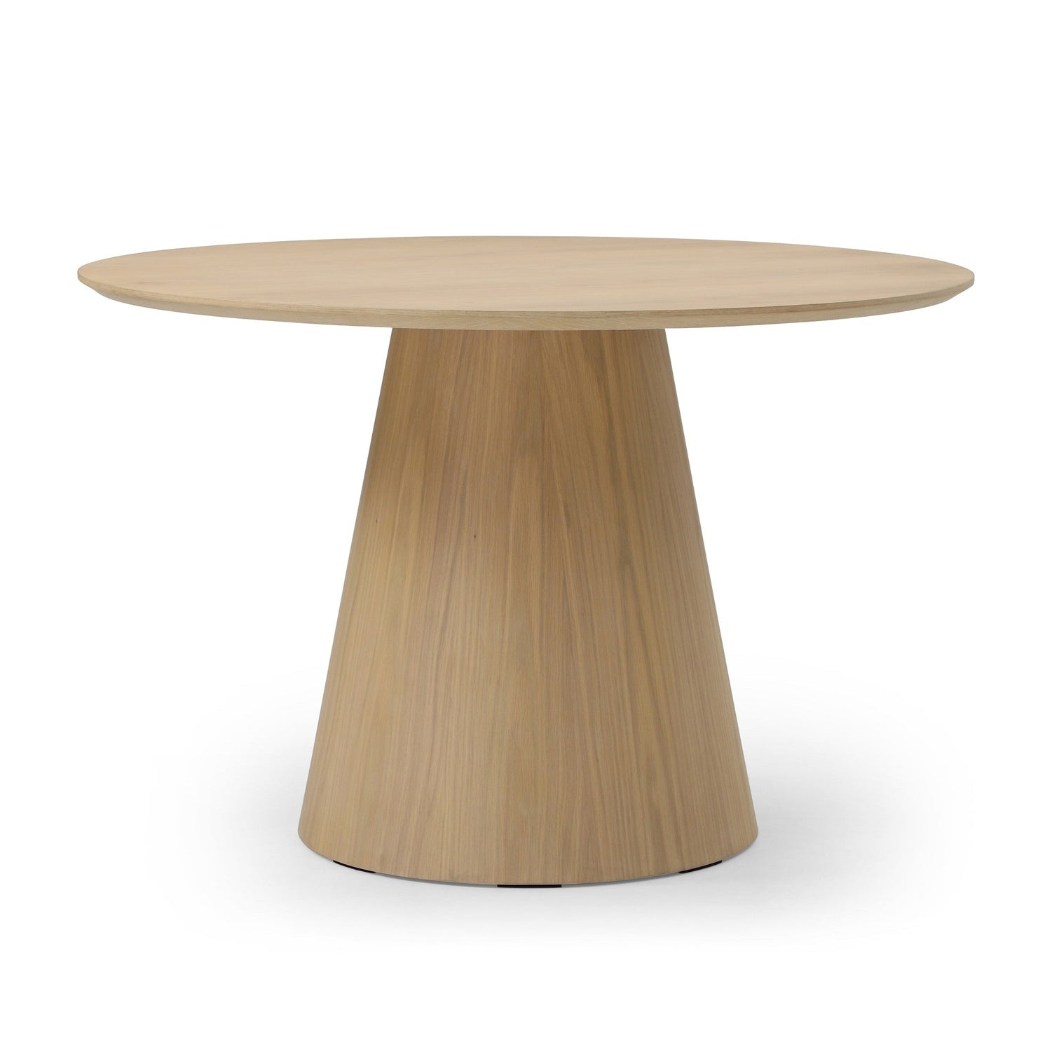 Three-quarter perspective view highlighting the clean architectural lines and smooth circular top of the oak dining table