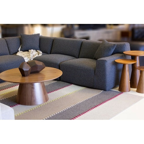 Front view of the Tower coffee table featuring a circular walnut tabletop with a thin beveled edge and a thick tapered pedestal base
