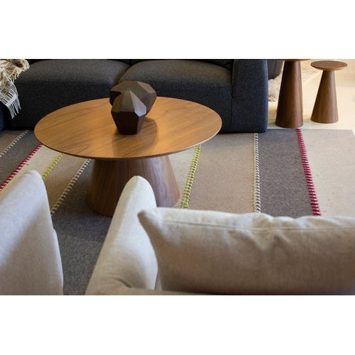 Front view of the Tower coffee table featuring a circular walnut tabletop with a thin beveled edge and a thick tapered pedestal base