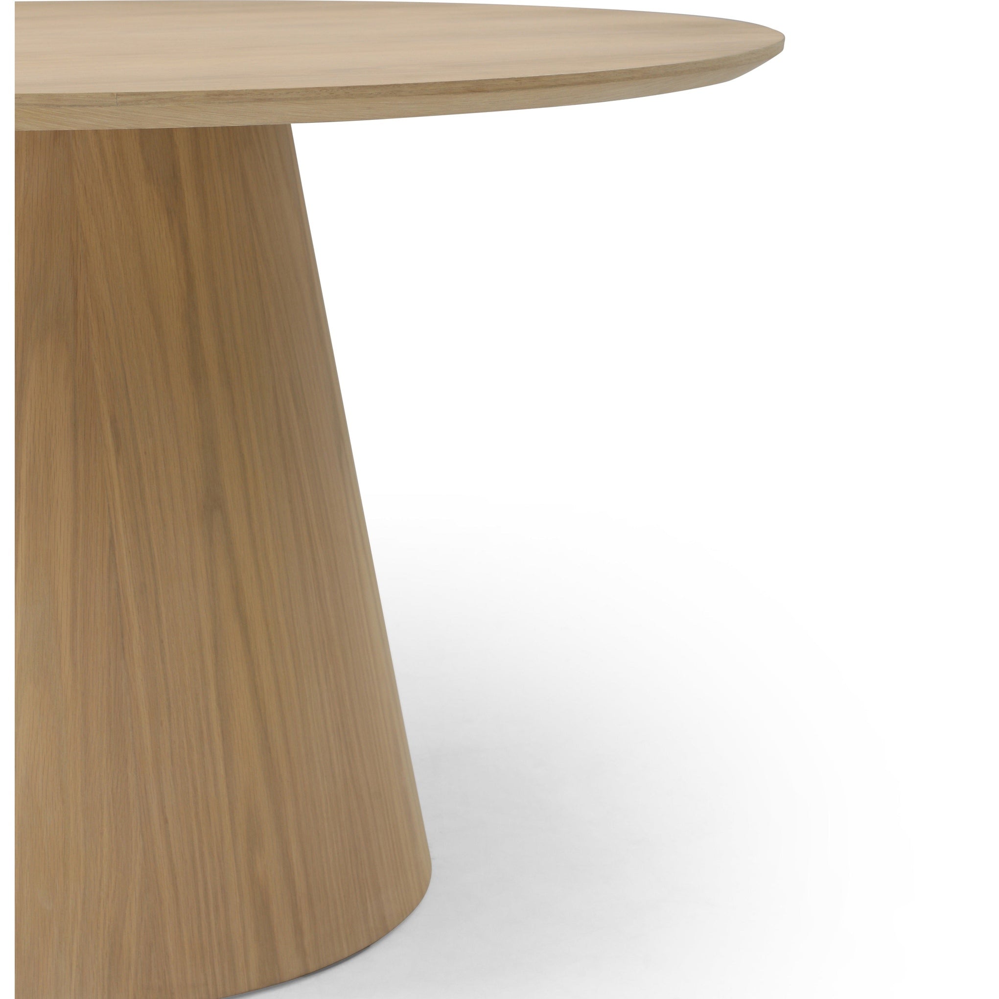 Three-quarter perspective view highlighting the clean architectural lines and smooth circular top of the oak dining table